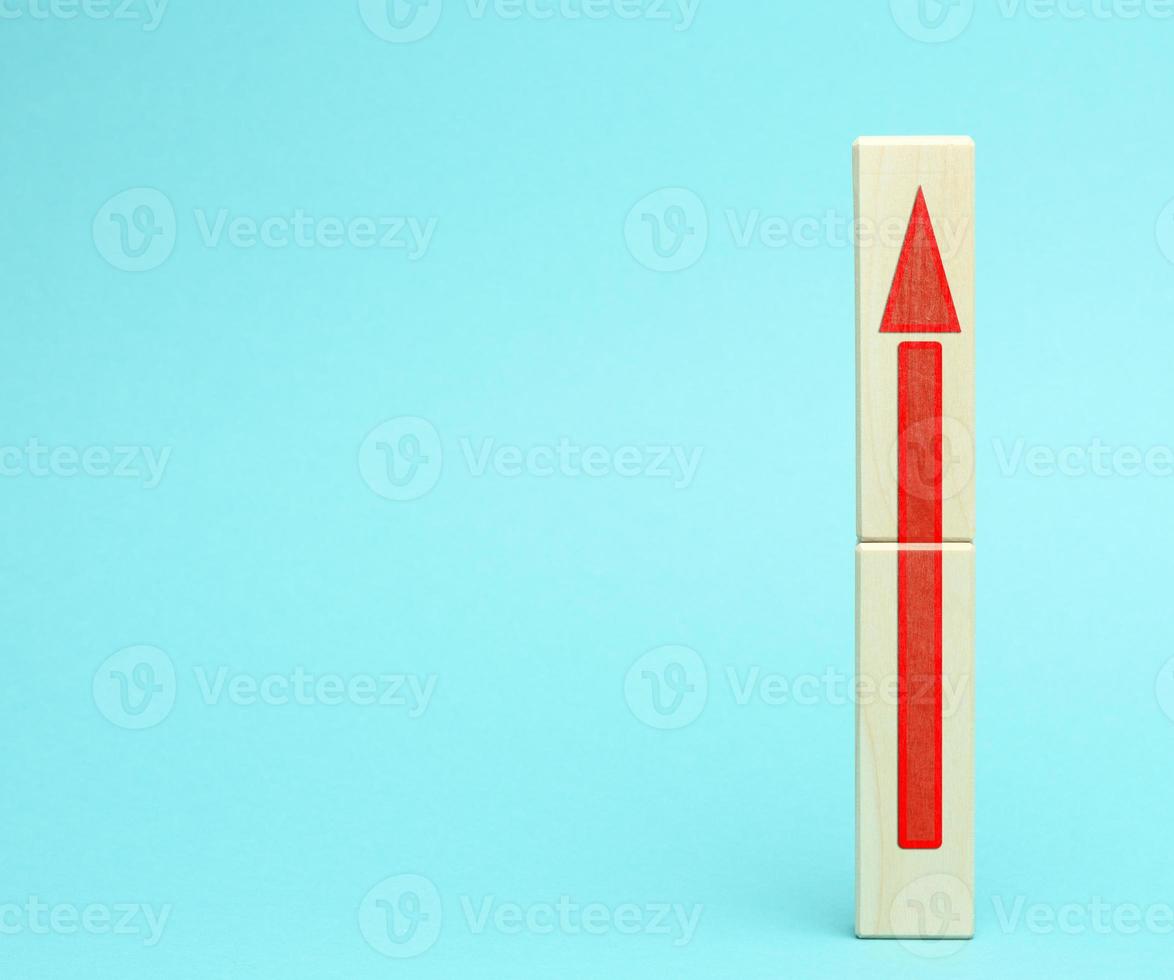 wooden block with an upward arrow on a bluee background, the process of growth and achievement of goals photo