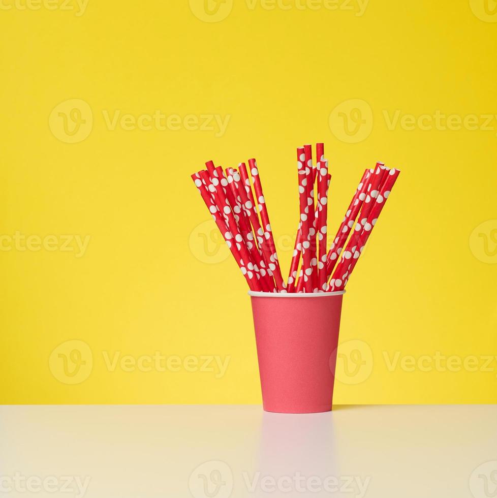 red cup with red paper cocktail tubes on white table, yellow background photo