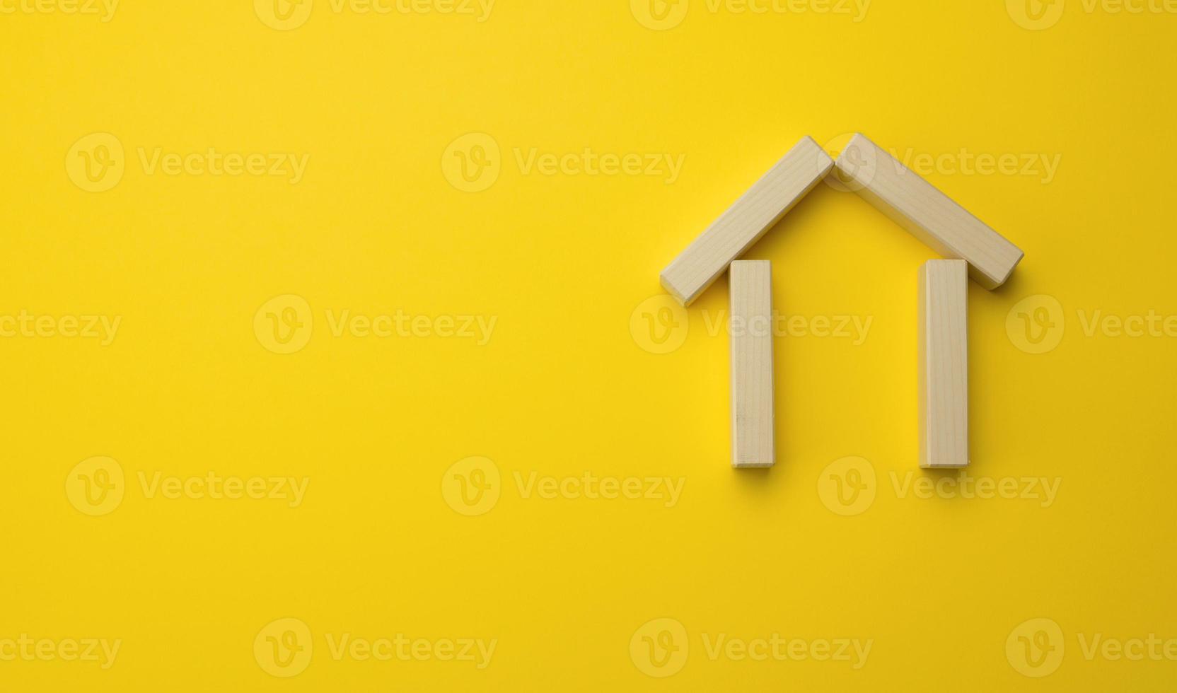 de madera miniatura casa en un amarillo antecedentes. el concepto de comprando y de venta un casa, alquiler y arrendamiento real inmuebles foto