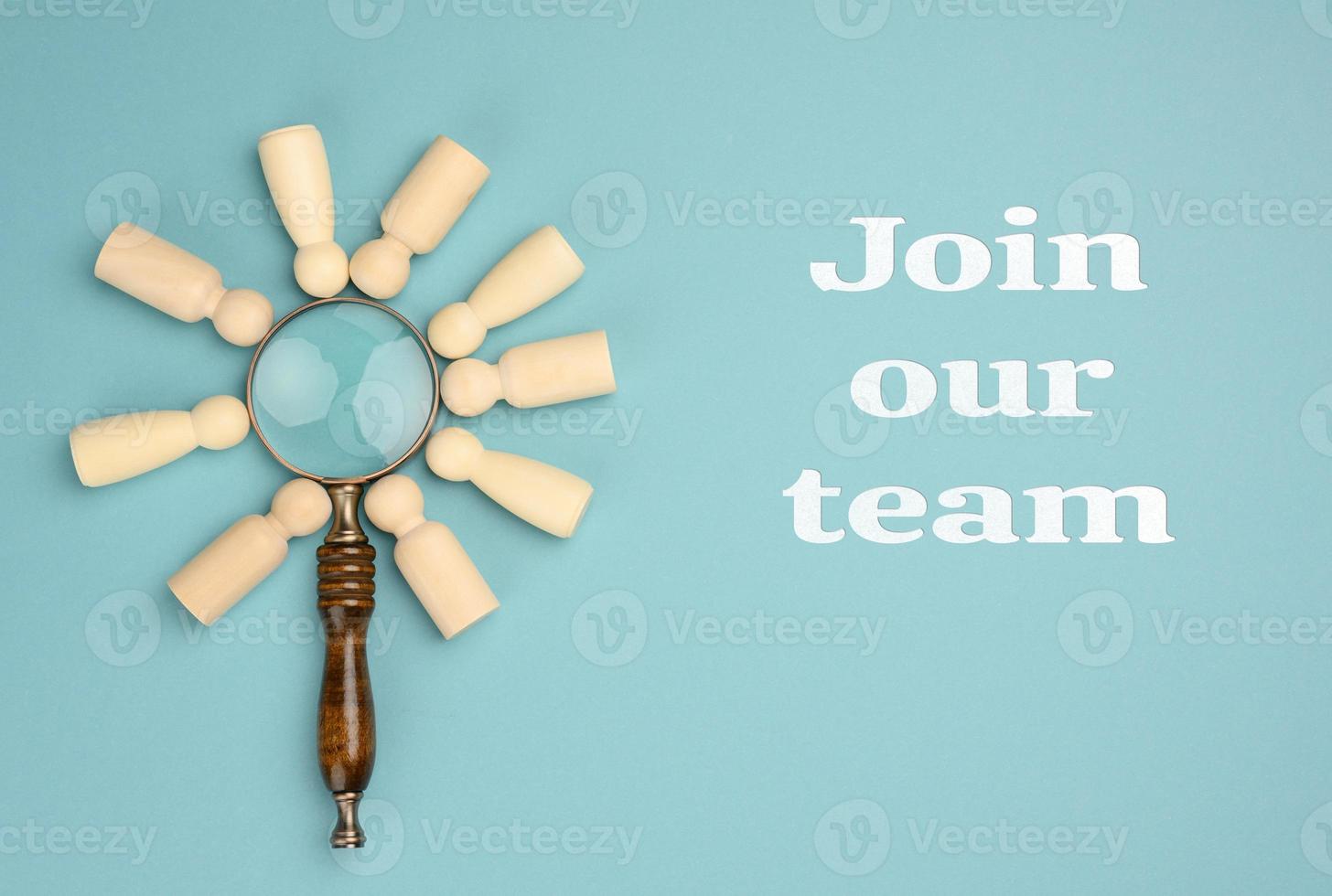 wooden men and a magnifying glass on a blue background. Recruitment concept, search for talented and capable employees, career growth photo