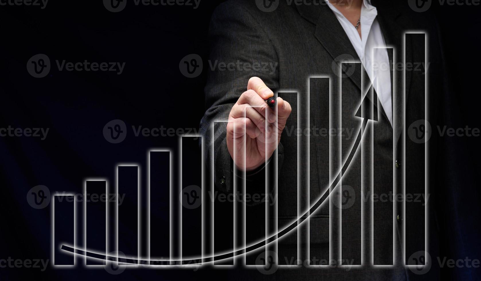 masculino empresario soportes en un negro traje en frente de un holográfico diagrama con gráficos y creciente indicadores. negocio crecimiento, ventas aumentar. alto actuación foto