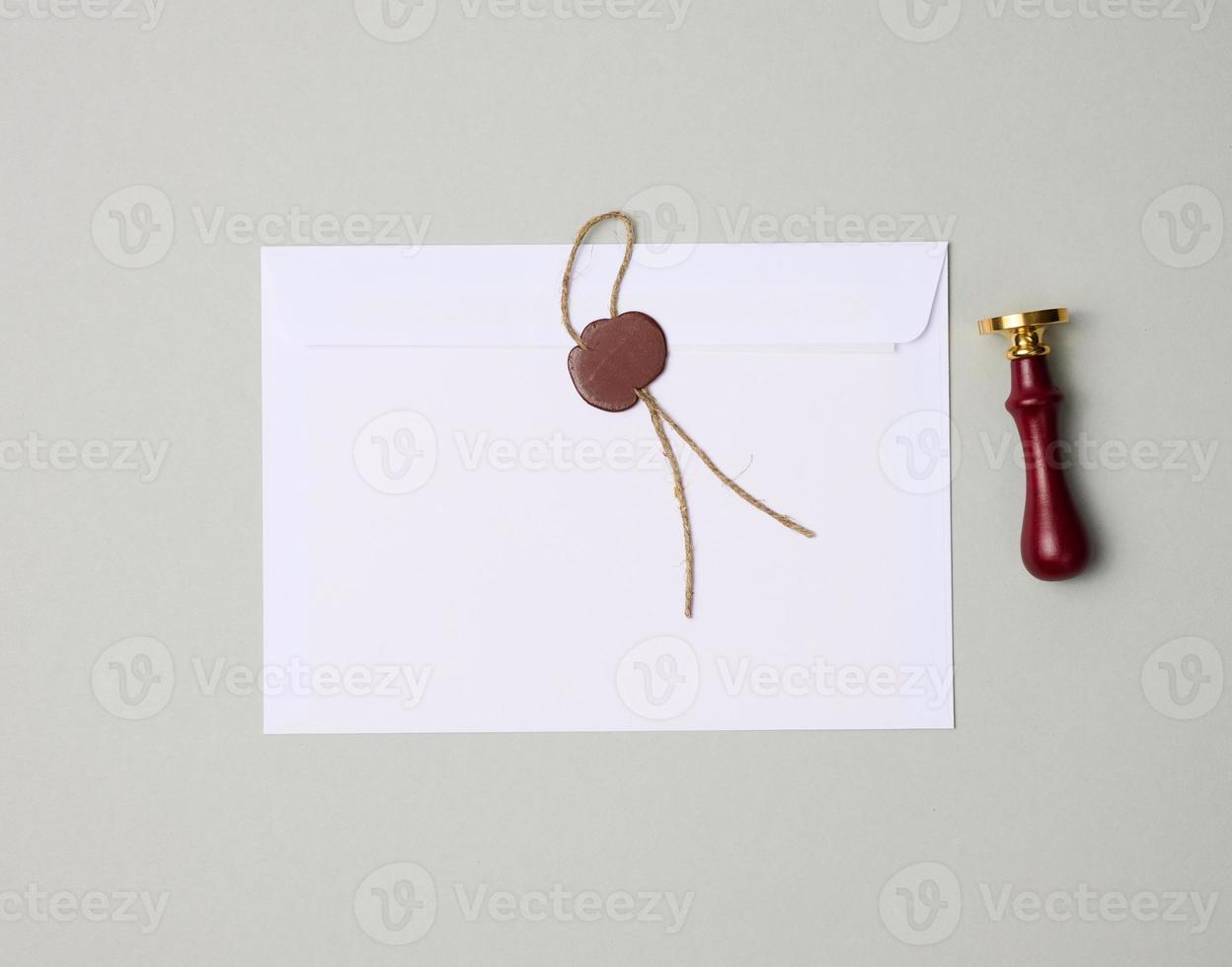 sealed white envelope with brown wax seal on gray background, flat lay photo