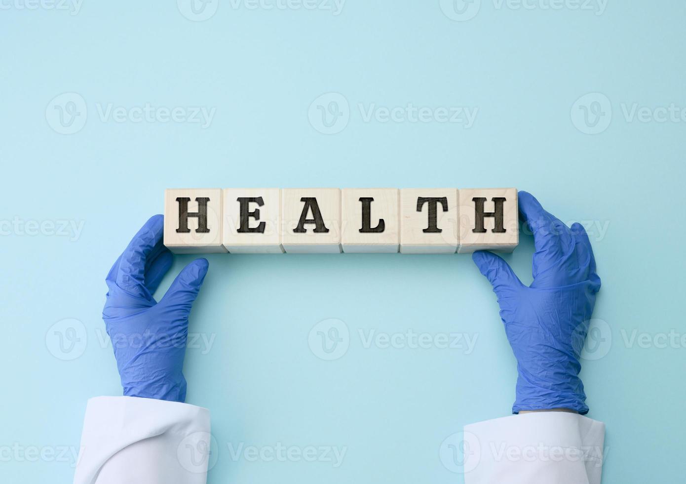 dos hembra manos son participación de madera bloques con el inscripción salud en un azul antecedentes. sano estilo de vida concepto foto