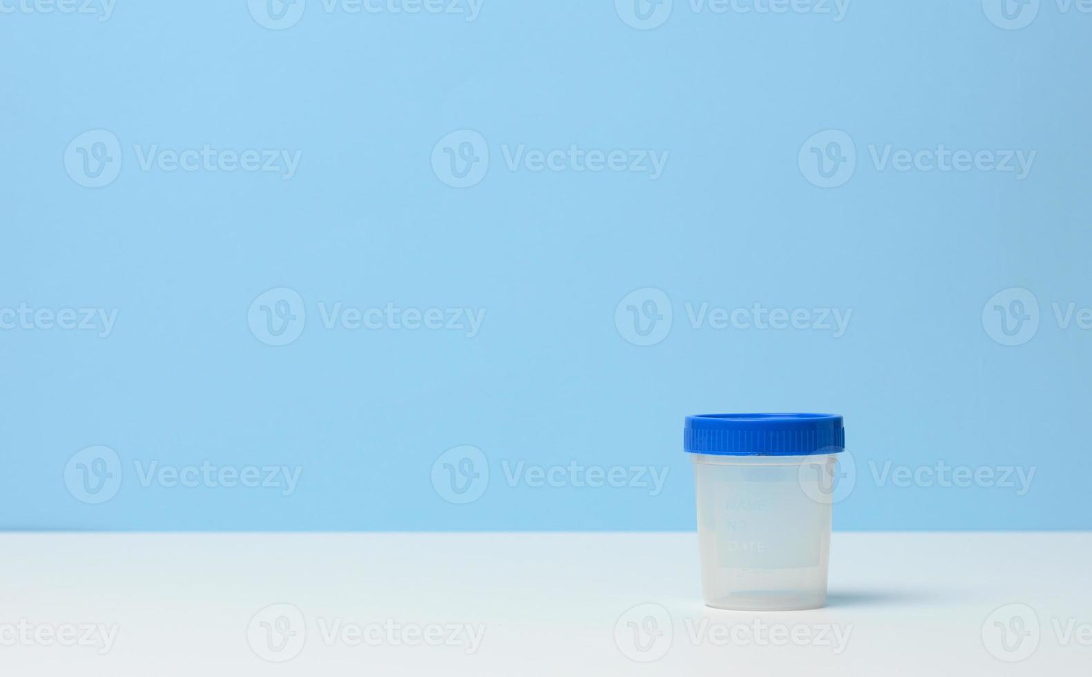 empty plastic container for the collection of analyzes on a white table, blue background photo