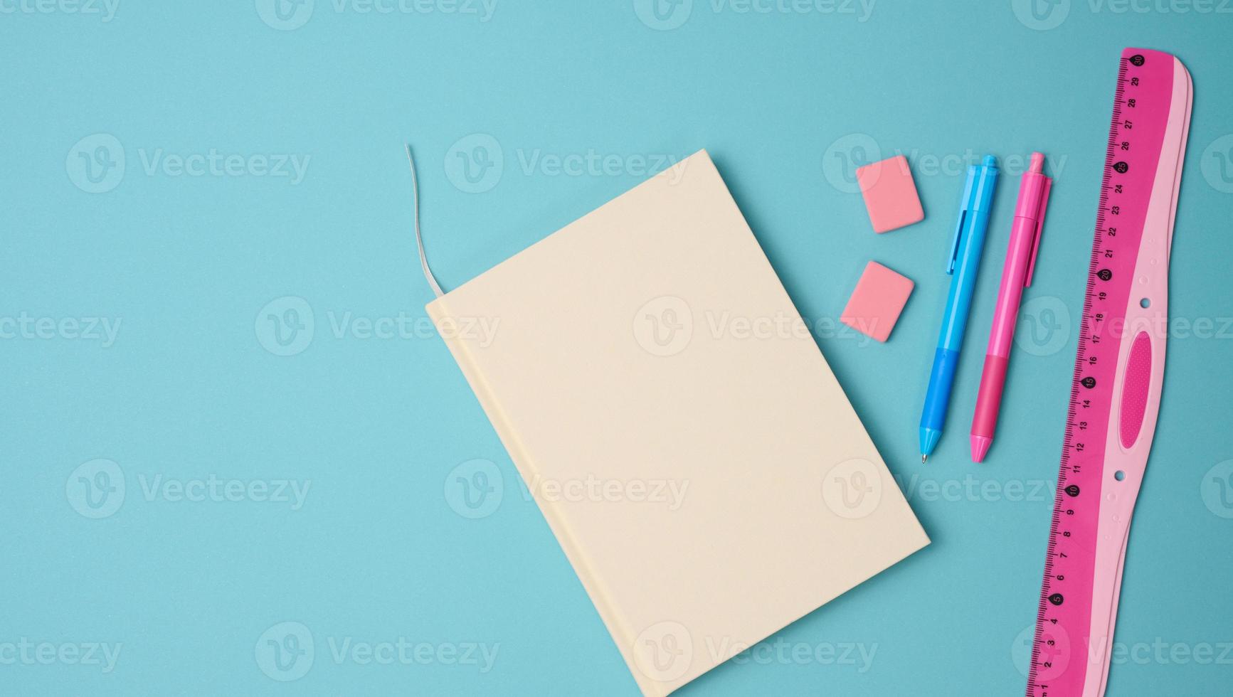 notebook and pink ruler on blue background, top view photo