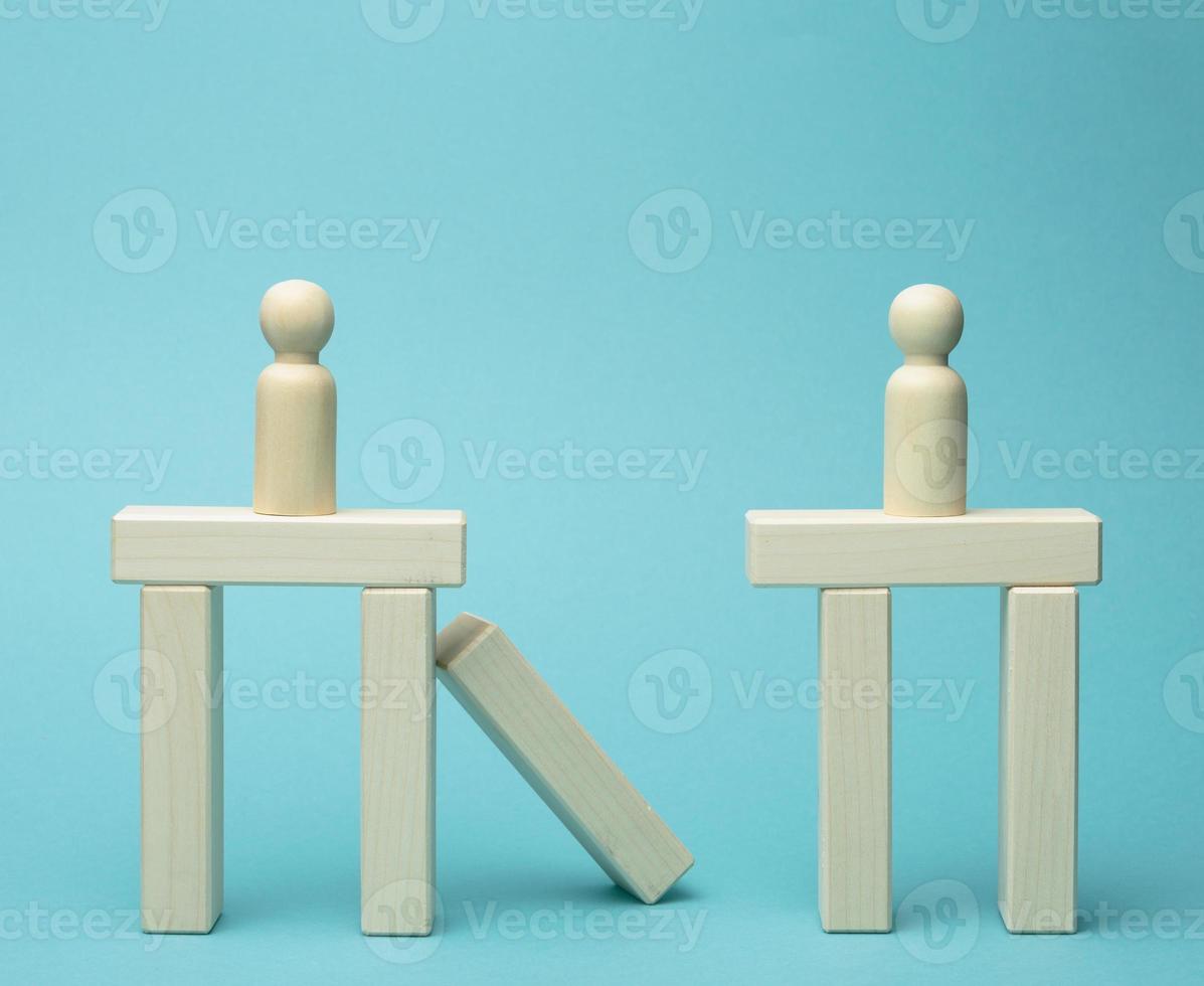 little wooden men stand on the destroyed bridge on different sides on a blue background photo