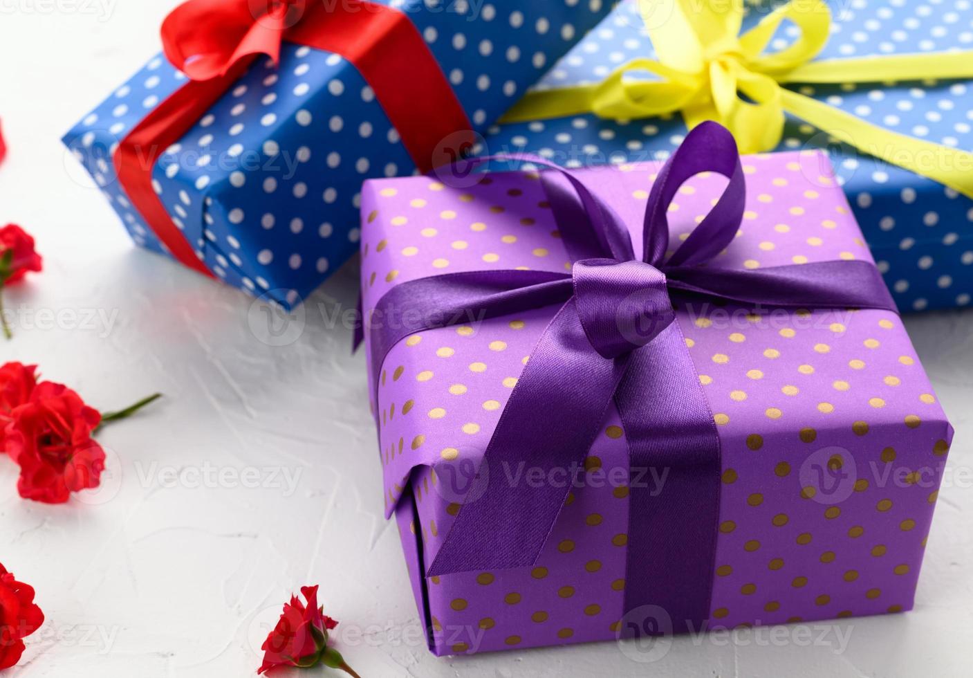 boxes packed in festive purple paper and tied with silk ribbon on white background, birthday gift, surprise photo