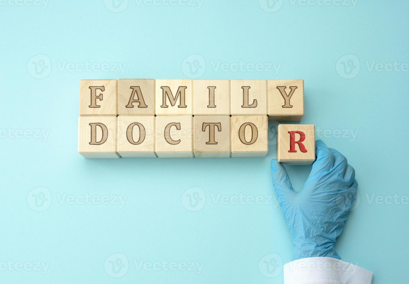 de madera bloques con el inscripción familia médico y un del doctor mano en un azul látex guante. foto