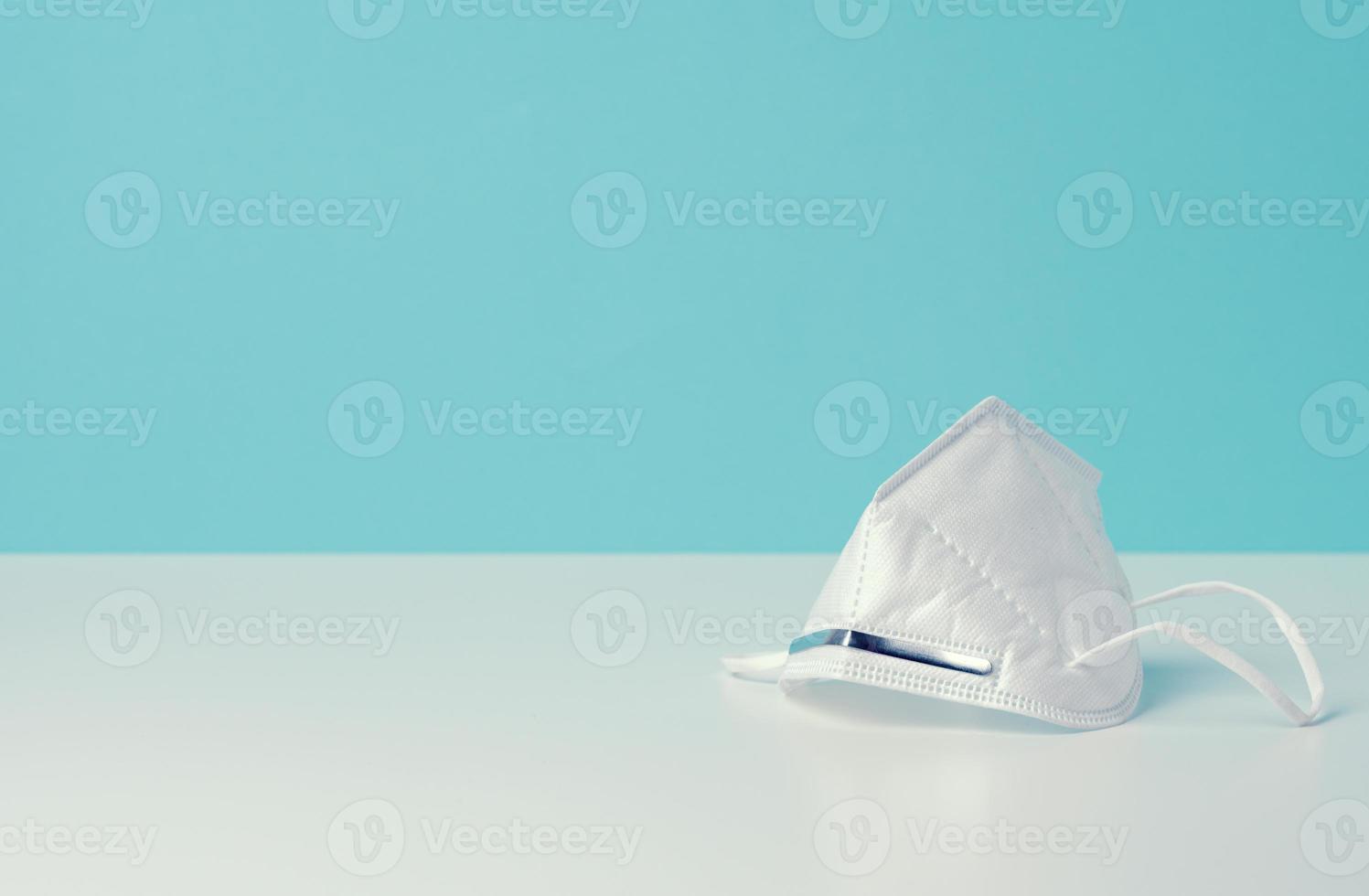 white disposable medical mask on a blue background, personal protective equipment for the respiratory tract from viral infections photo