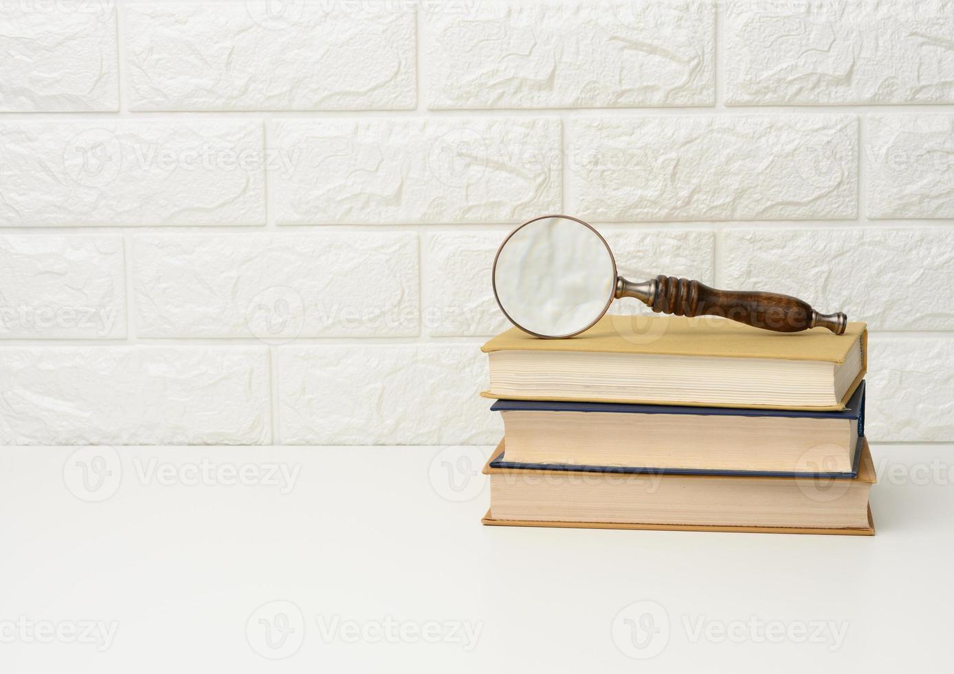 a wooden magnifying glass lies on a stack of books, new knowledge and discoveries are reading books photo