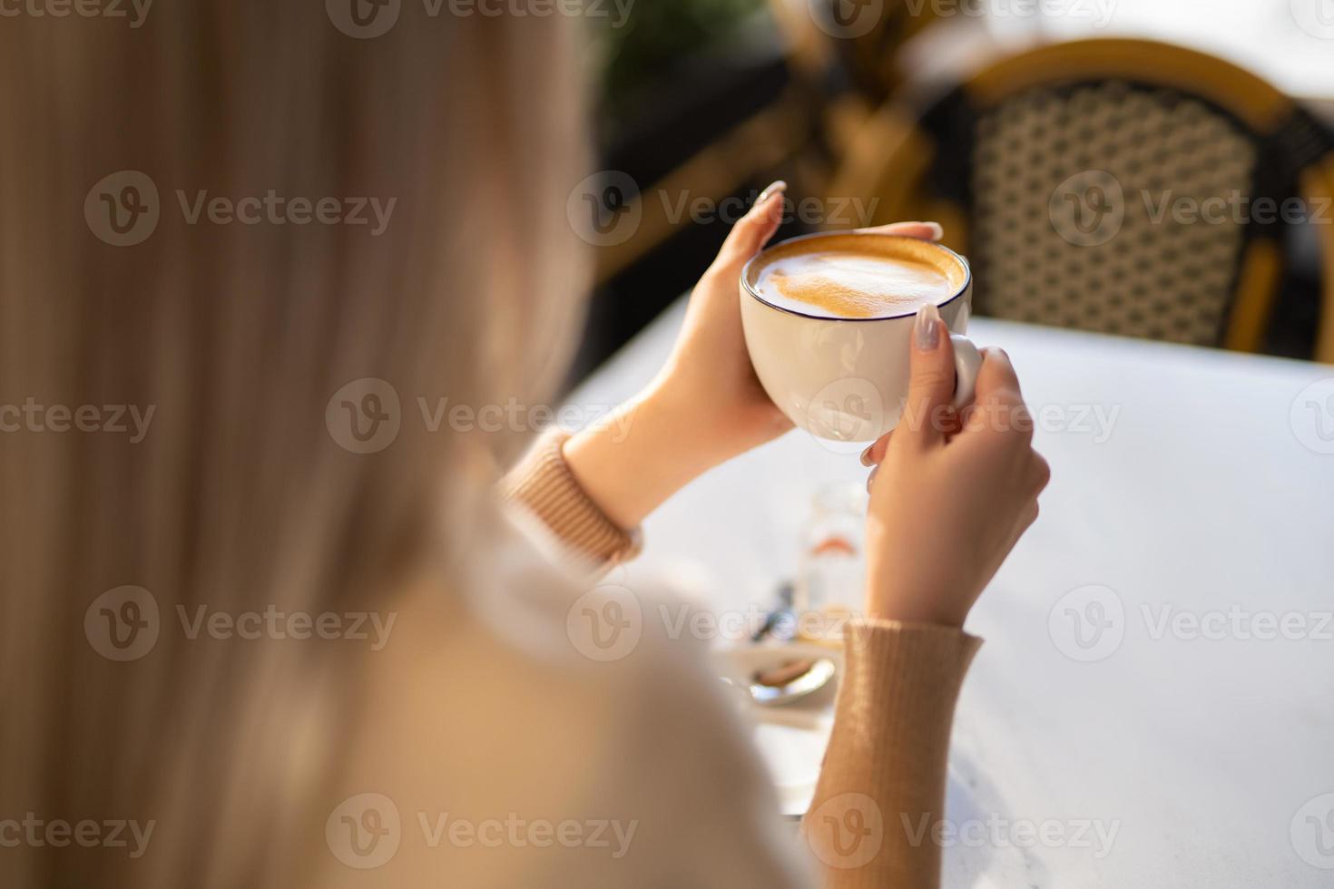 a fragrant and warm mug of cappuccino with a drawing heart,  girl  hold in hands. photo