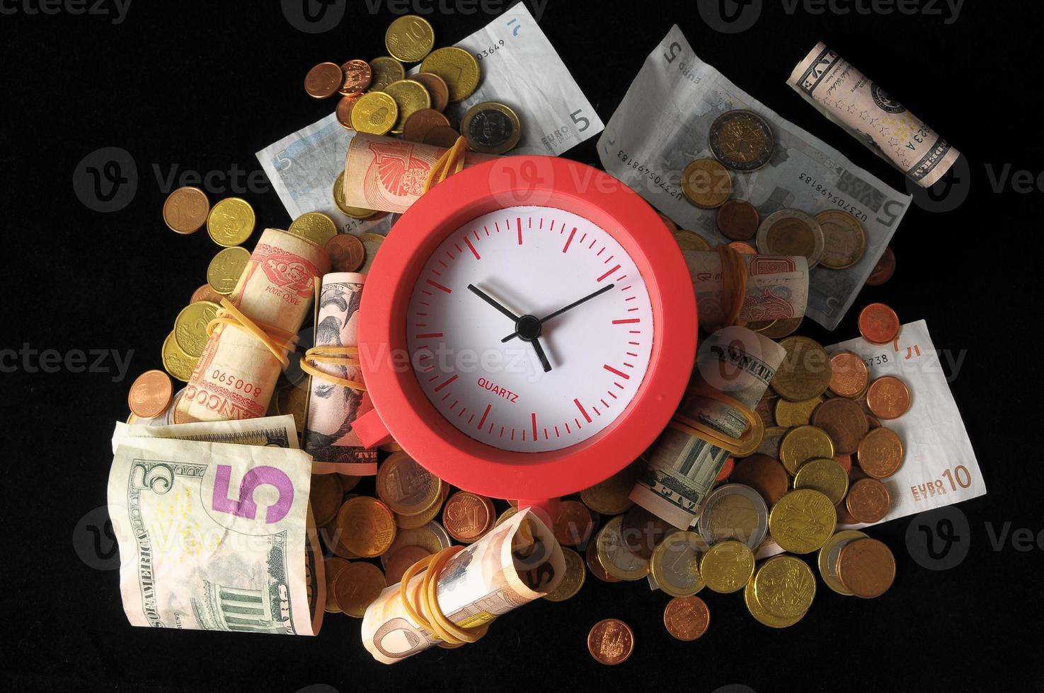 Coins, banknotes and a clock on black background photo