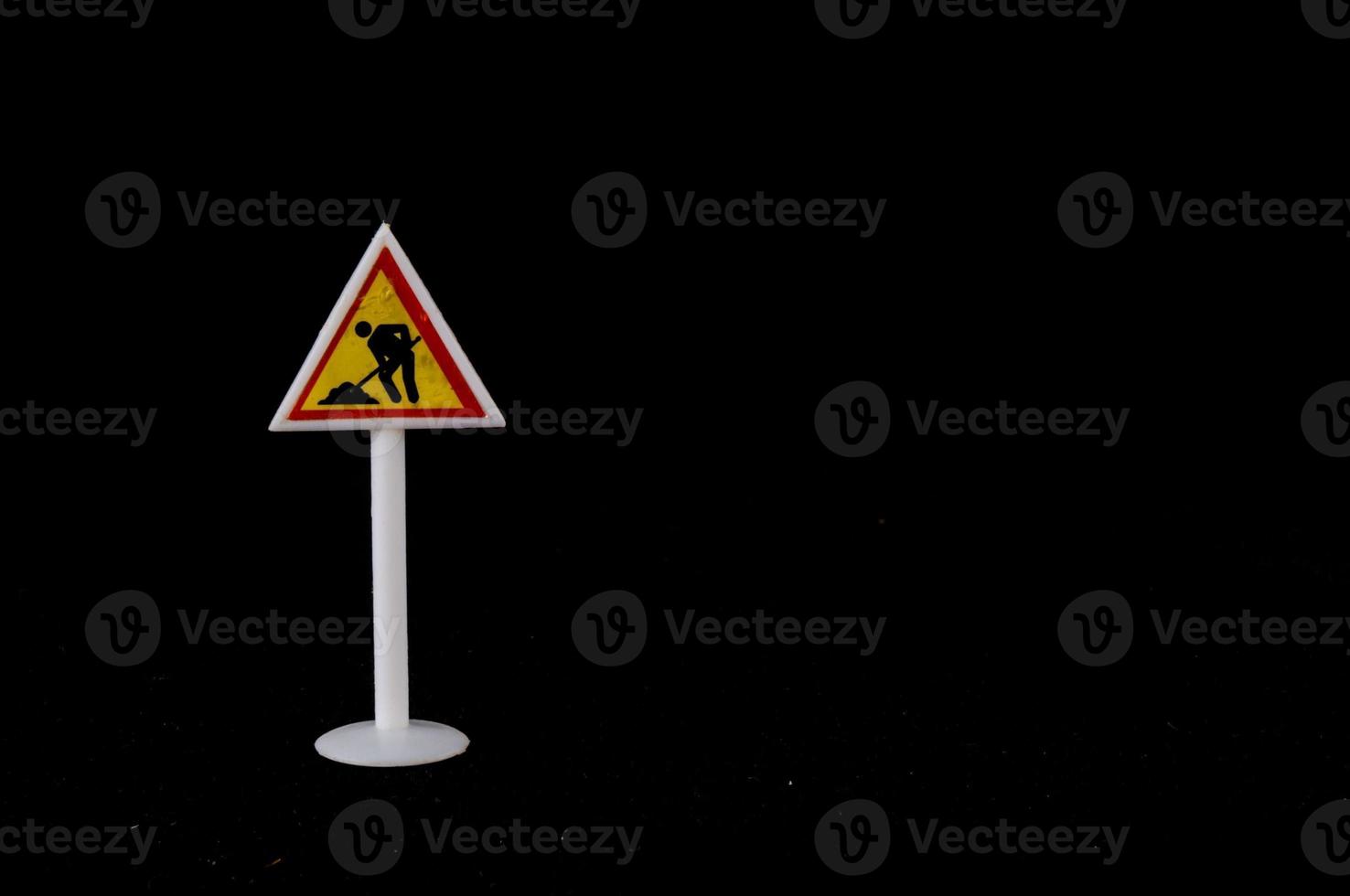 Toy road sign on black background photo