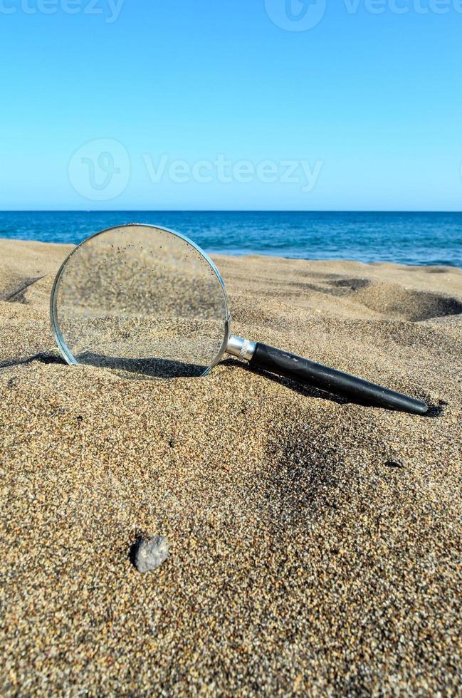 Magnifying glass on the sand photo