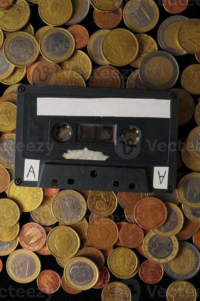 Cassette laying on a pile of coins photo