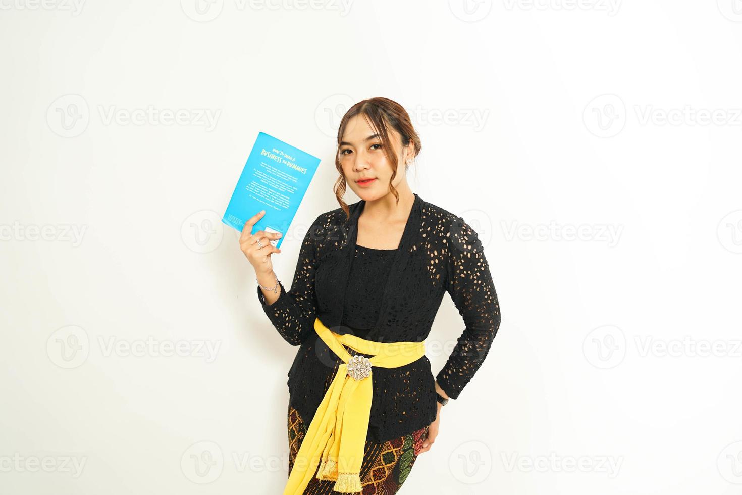 Balinese woman holds a book while adorned in traditional attire, showcasing the  blend of culture and education. photo