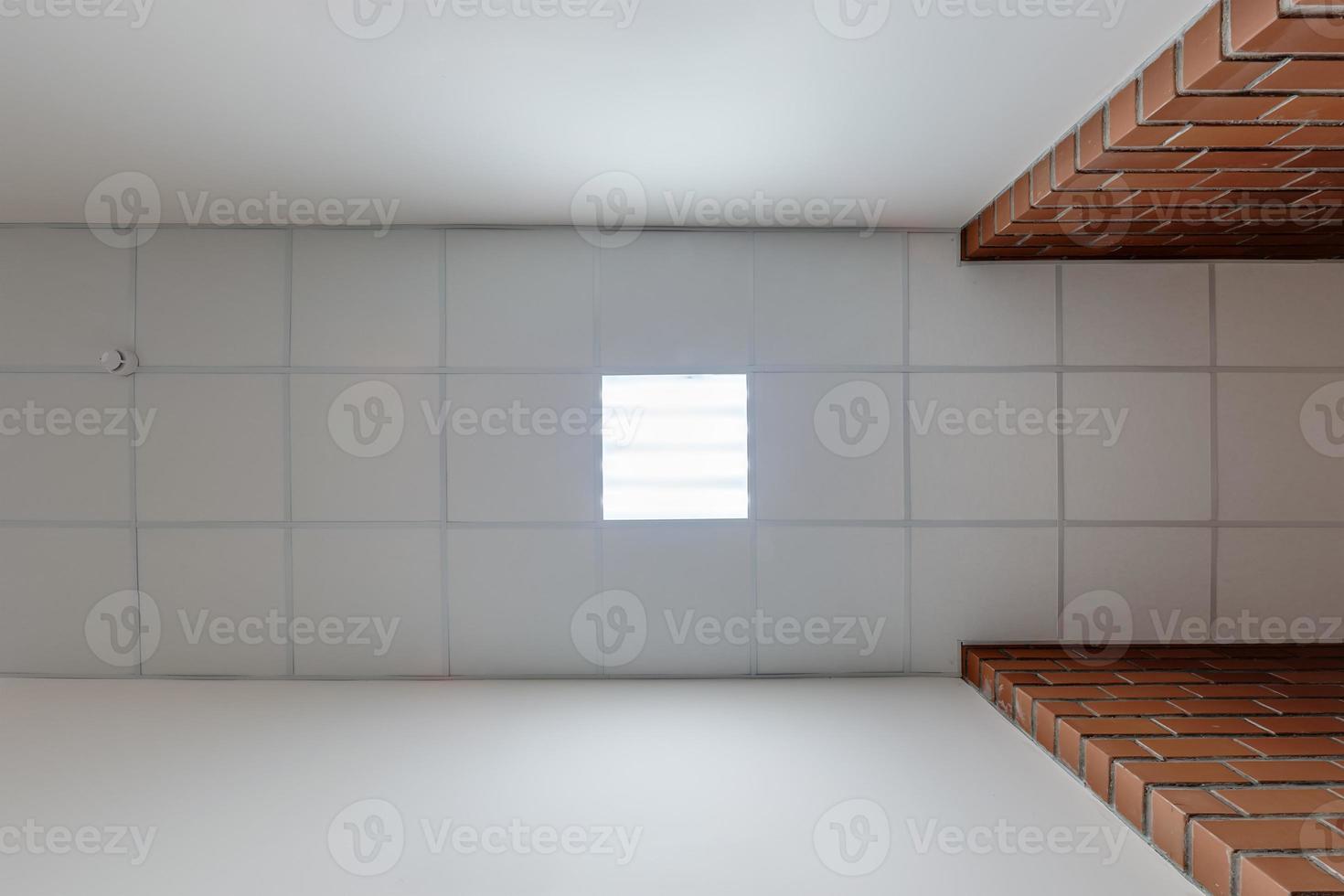 cassette stretched or suspended ceiling with square halogen spots lamps and drywall construction in empty room in house or office with column. Looking up view photo