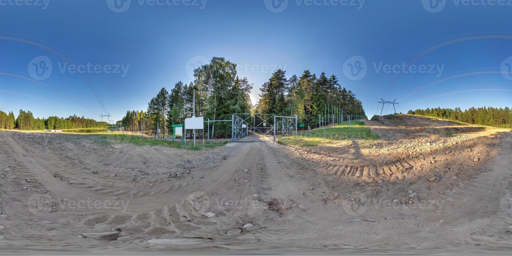 full seamless hdri 360 panorama on gravel road in front of fence of forbidden zone, border or reserve in pinery forest in equirectangular spherical projection near power lines and high voltage poles photo