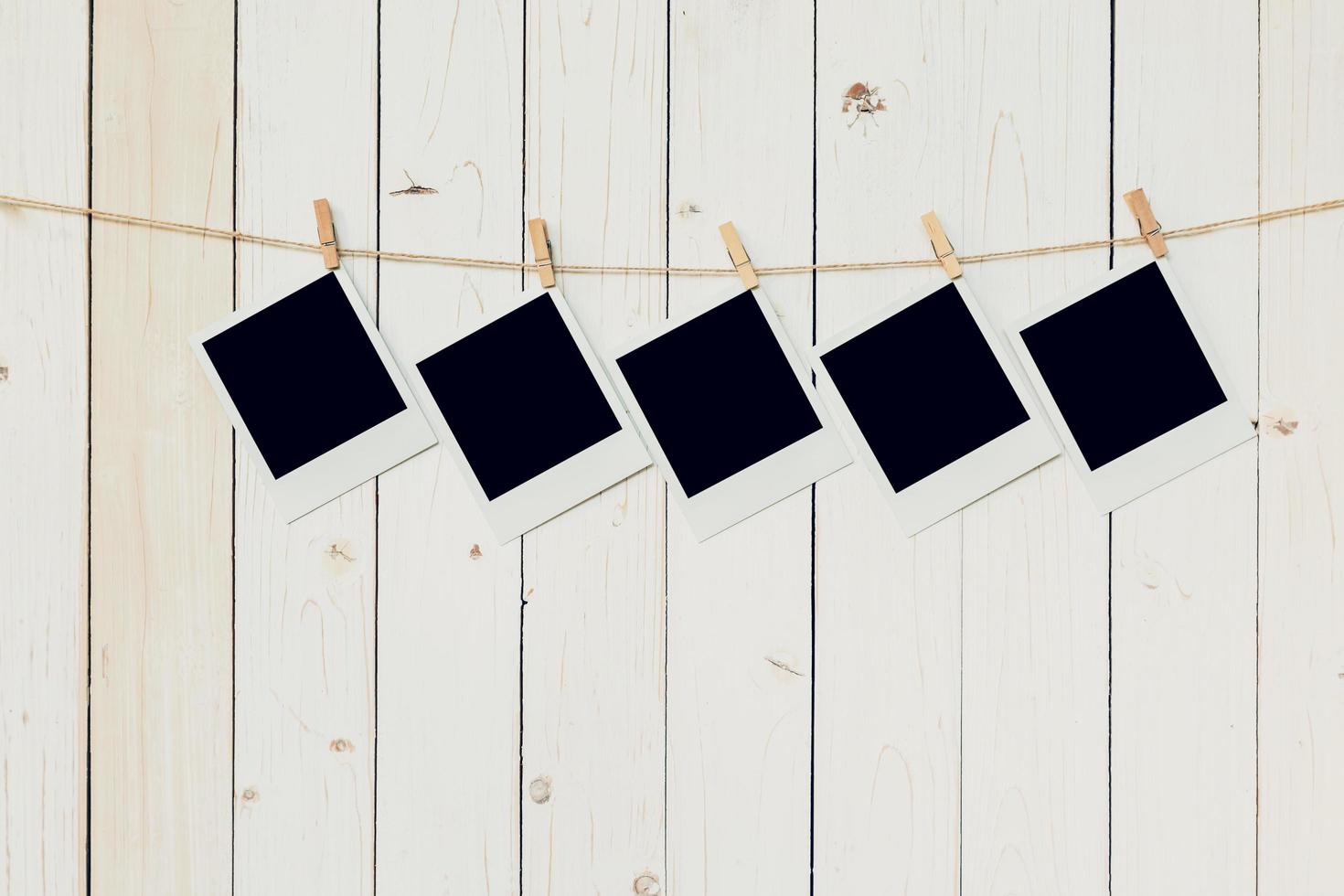 Five blank photo frame hanging on white wood background with space.