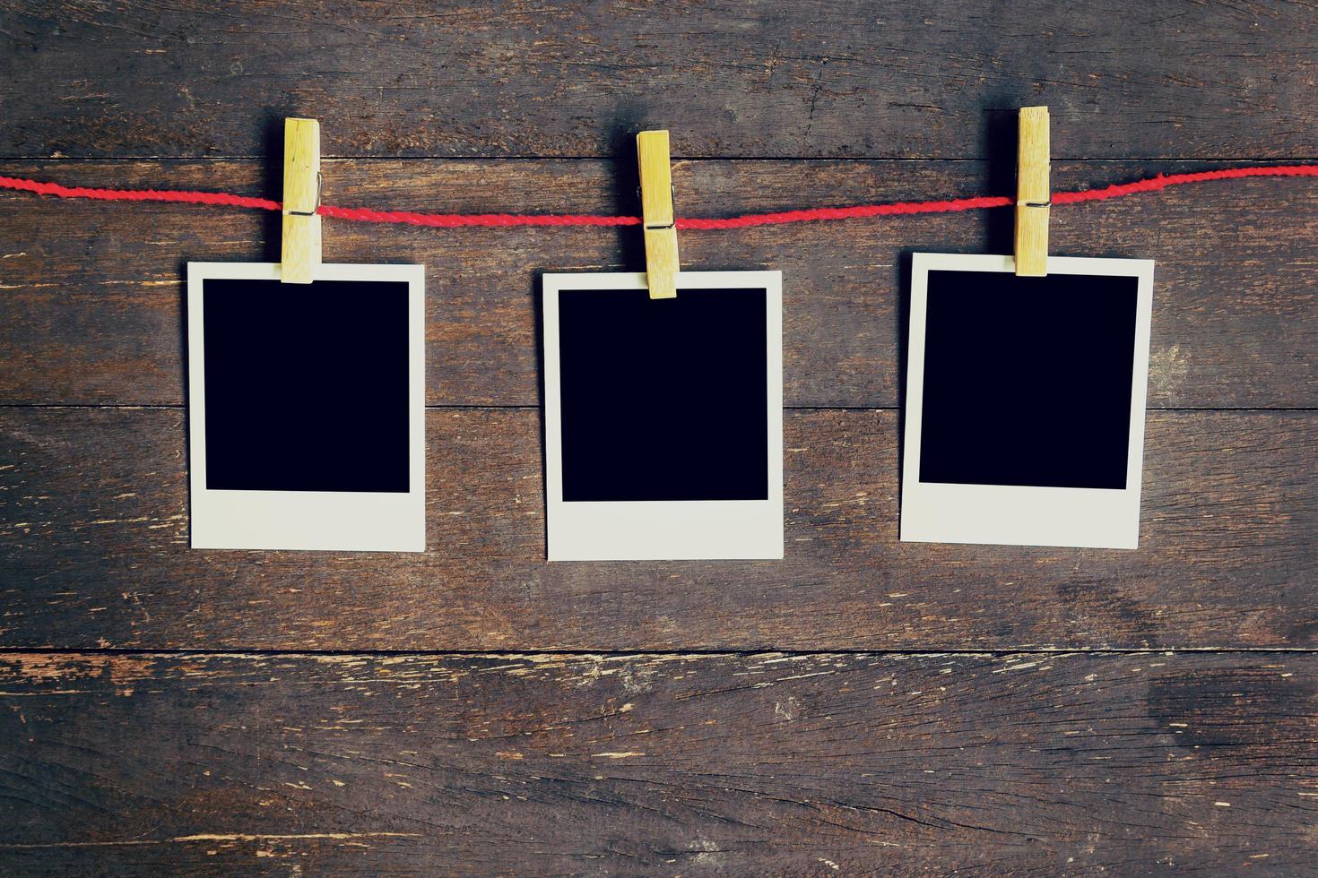 Three blank photos frame hanging on the clothesline. On old wood background.