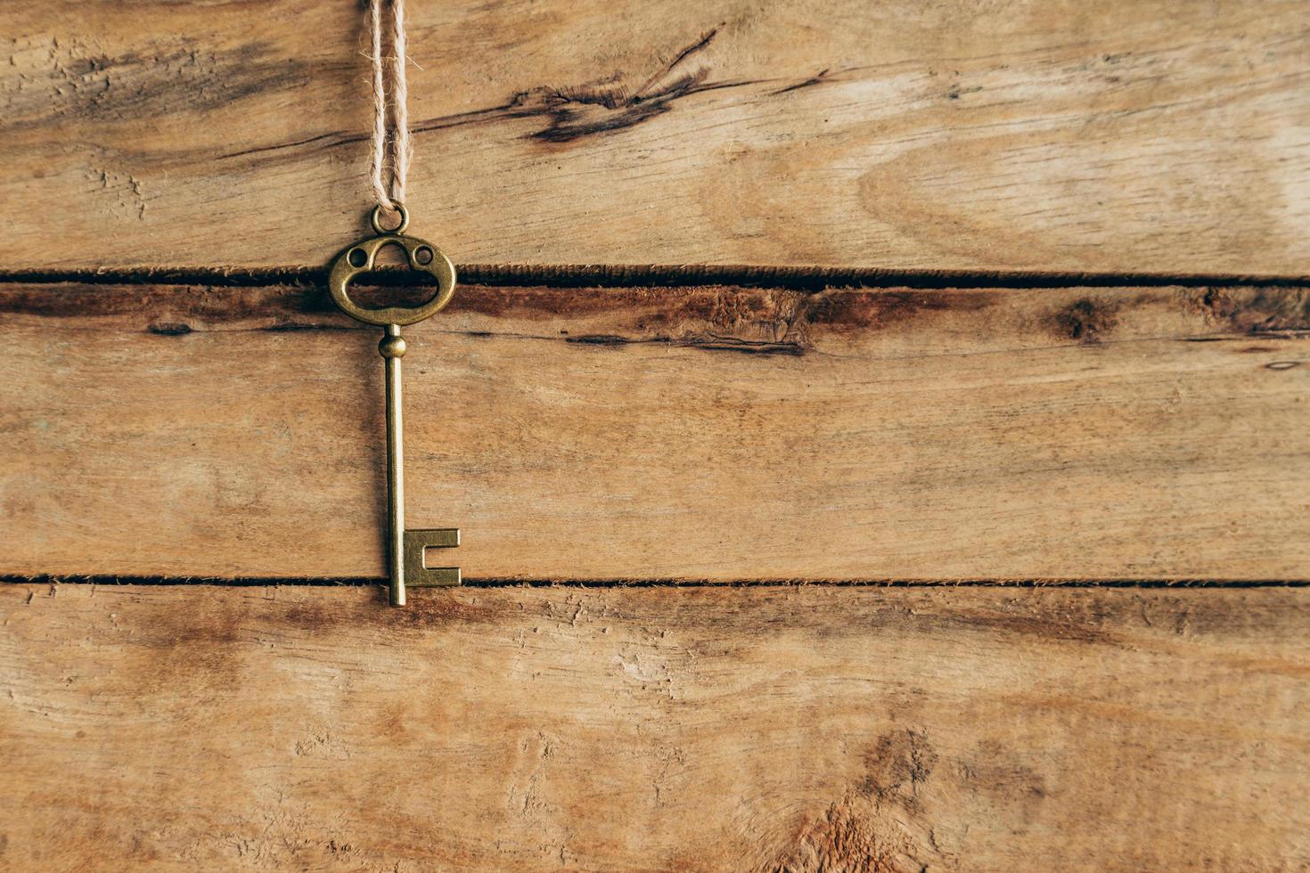 Old key hanging on brown wood with space. photo