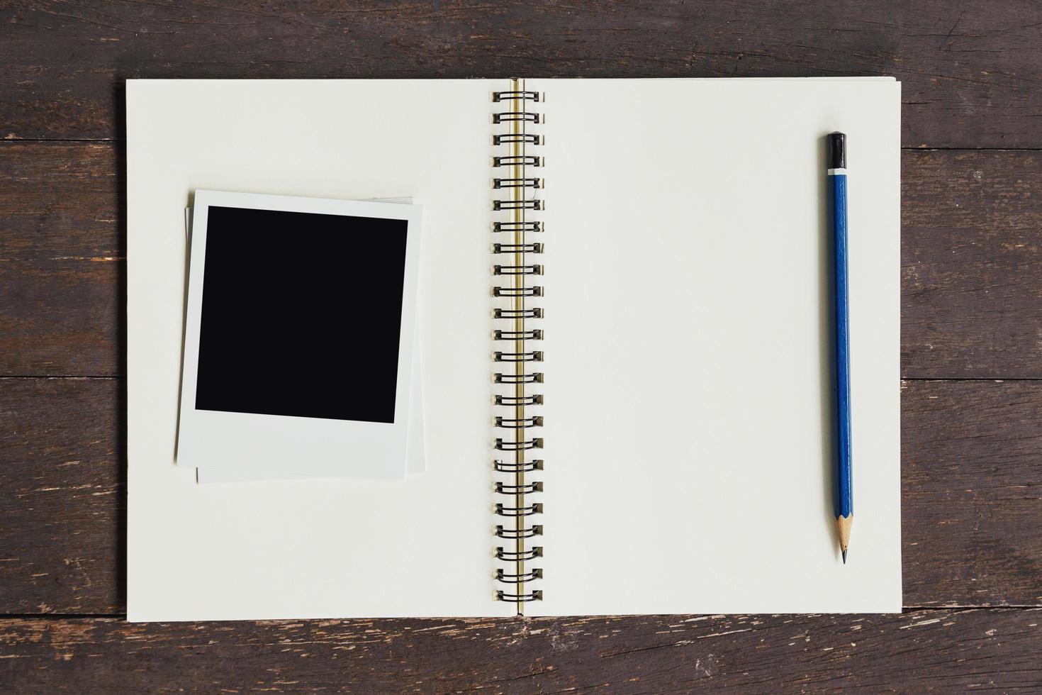 Frame photo and brown book on wood table background.