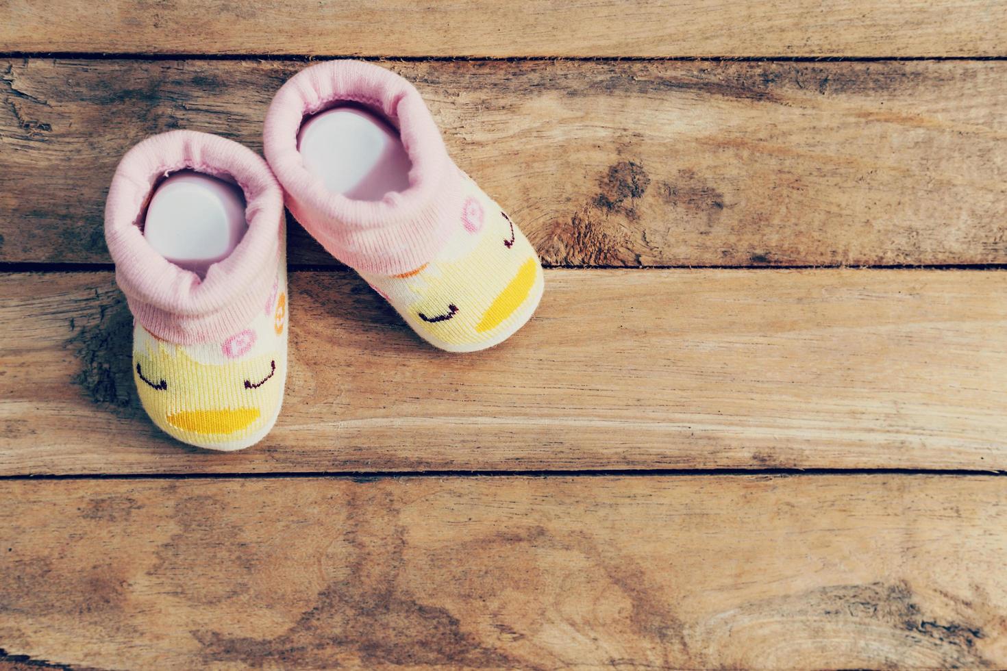 Baby shoes on wooden background with space photo