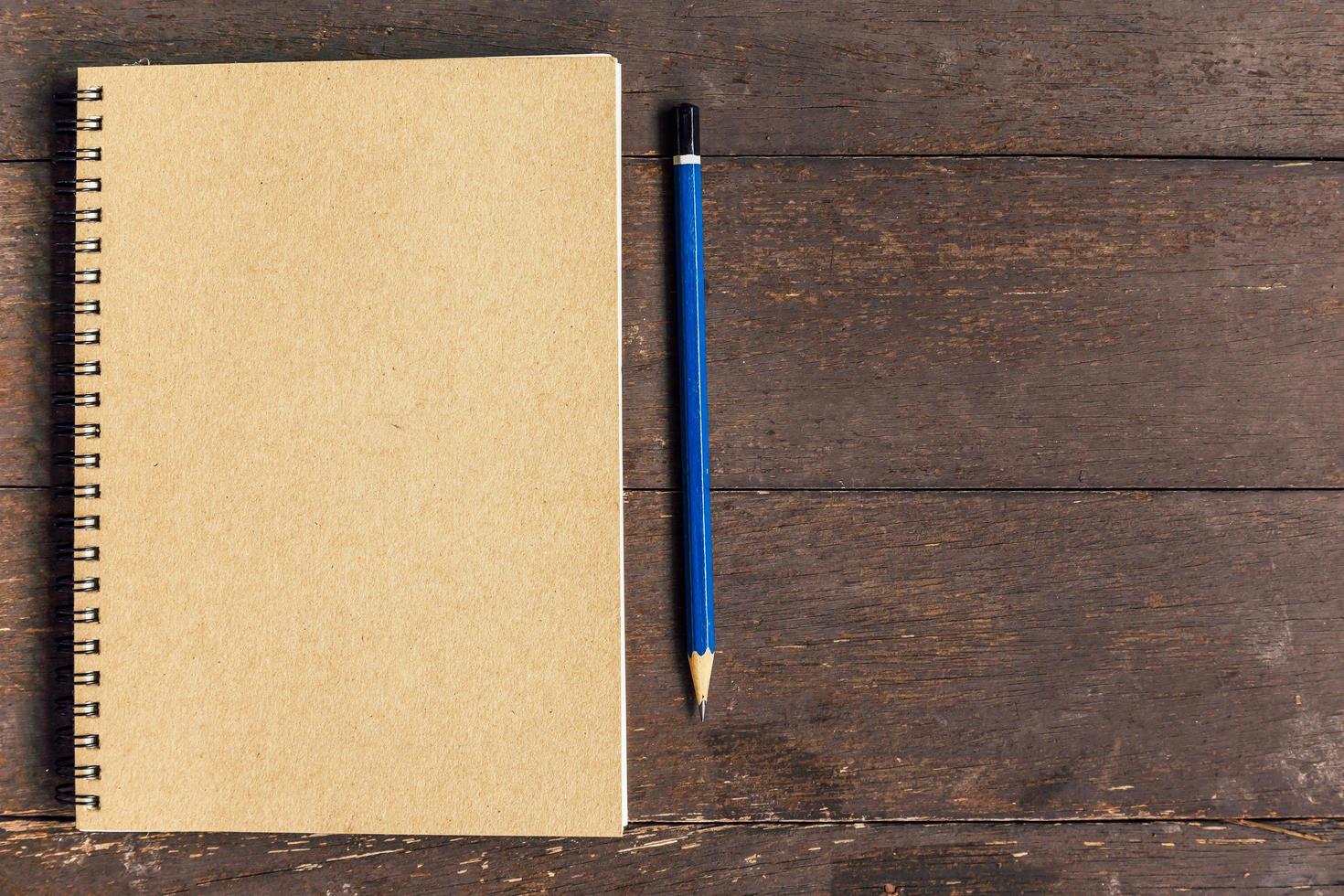 brown book and pencil on wood table background with space photo