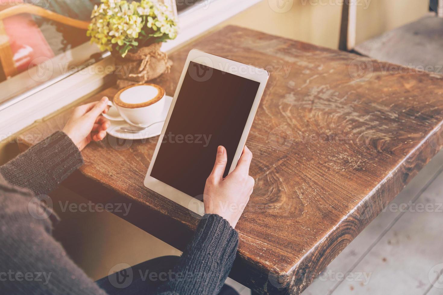 close up hand asian woman using tablet computer in coffee shop with vintage toned. photo