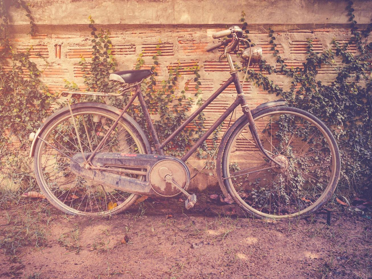 antiguo Clásico bicicleta estacionamiento a grunge pared casa con retro filtrar. foto