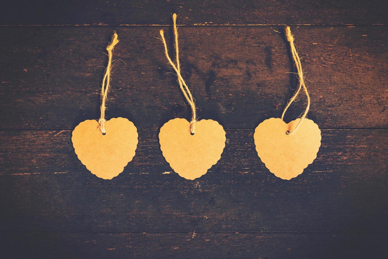 Blank brown tag heart shape on old wood background with space. photo