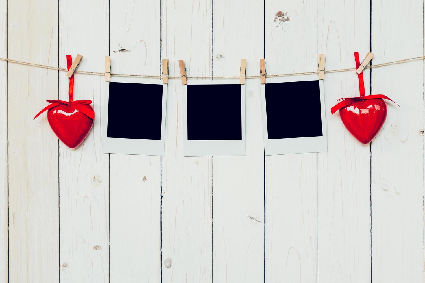 three photo frame blank and red heart hanging on white wood background with space