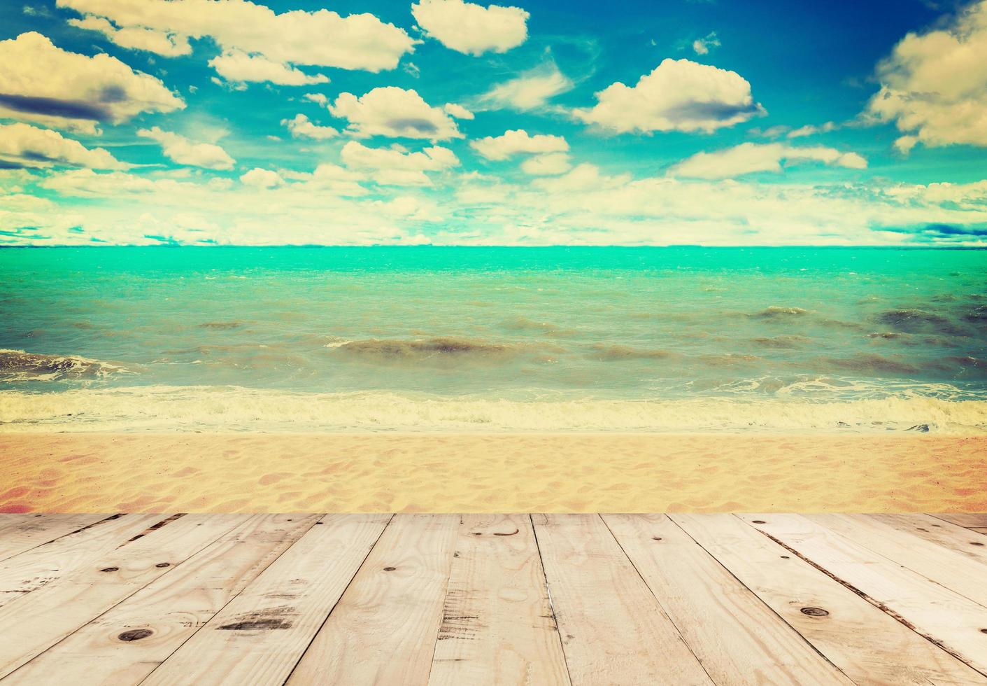 Wood table sand beach sea and in sky clouds with vintage tone. photo