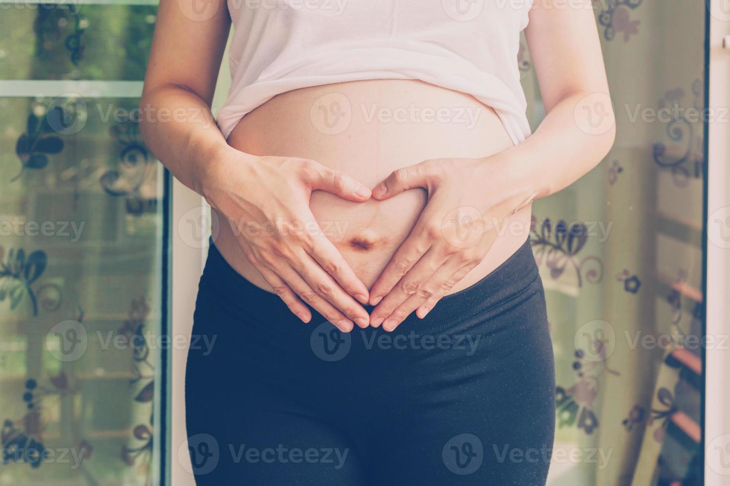 embarazada mujer participación mano corazón forma para bebé en su barriguita foto