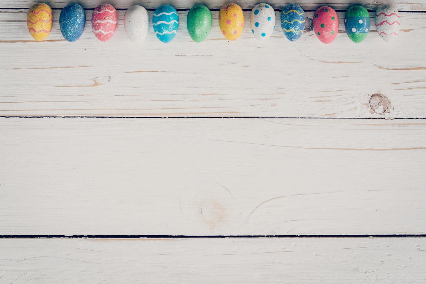 Easter eggs on wooden background. Pastel colorful easter eggs and hand paint on wooden background. photo