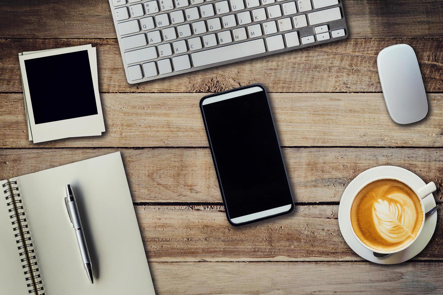Office table with coffee cup, computer, phone, notebook and pen. View from above with copy space photo