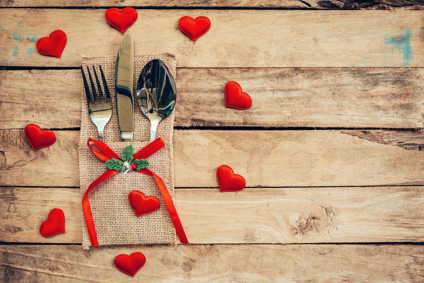 Table set for celebration Valentine's Day. Wooden table place setting and silverware with red heart for Valentine day. photo