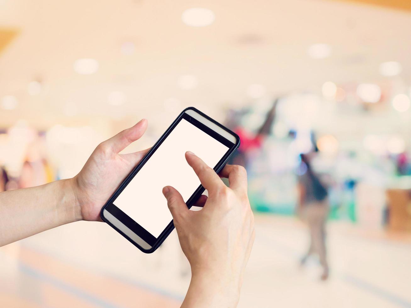 Hand woman holding and using phone with blurred background in shopping mall. photo