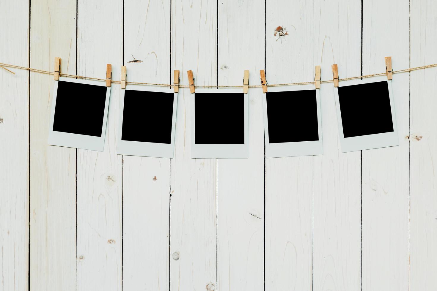 Five blank photo frame hanging on white wood background with space