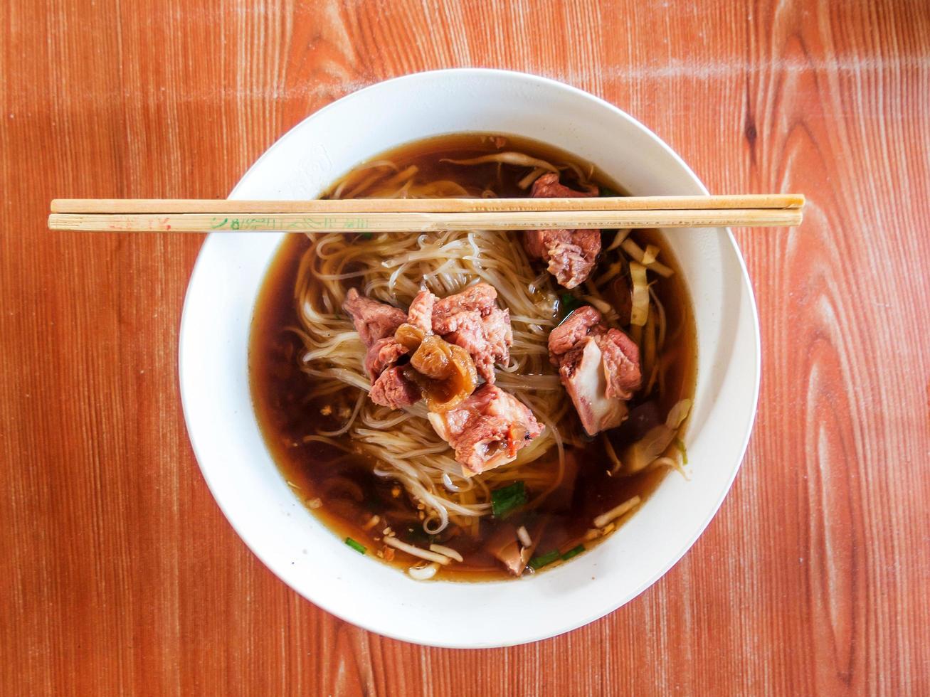 tailandés fideos sopa con carne en madera mesa foto