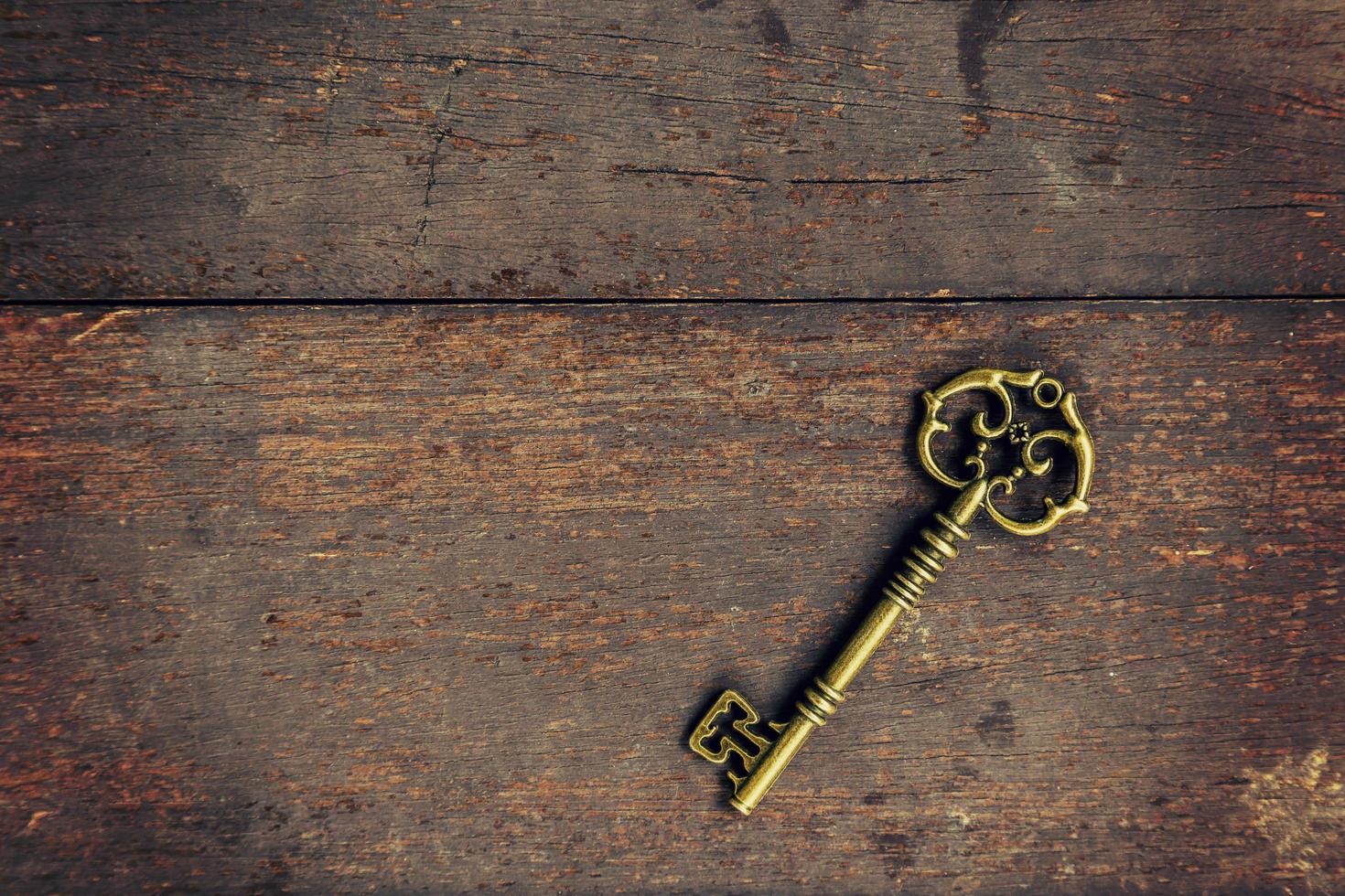 Old vintage key on wood texture background with space photo