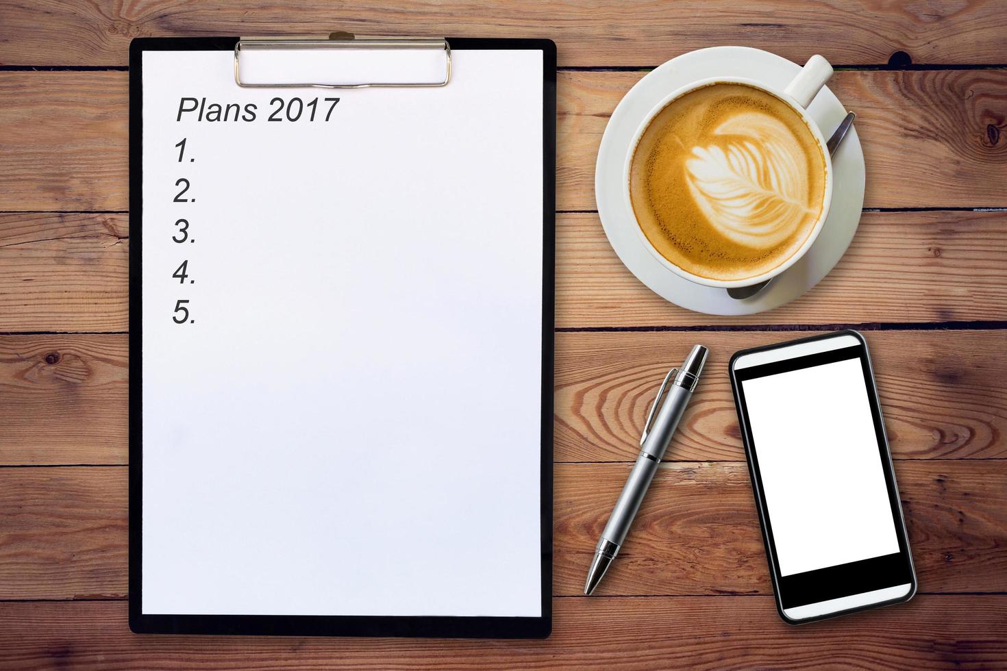 Business concept - Top view clipboard writing Plans 2017, pen, coffee cup, and phone on wood table. photo