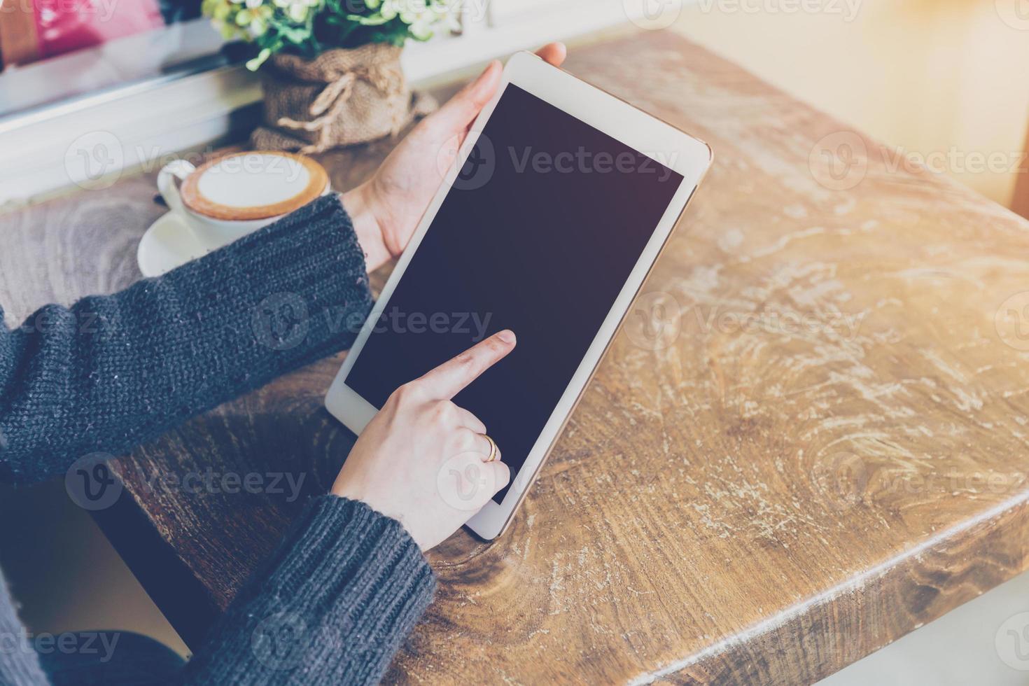 Close up hand woman using tablet in coffee shop with vintage tone. photo