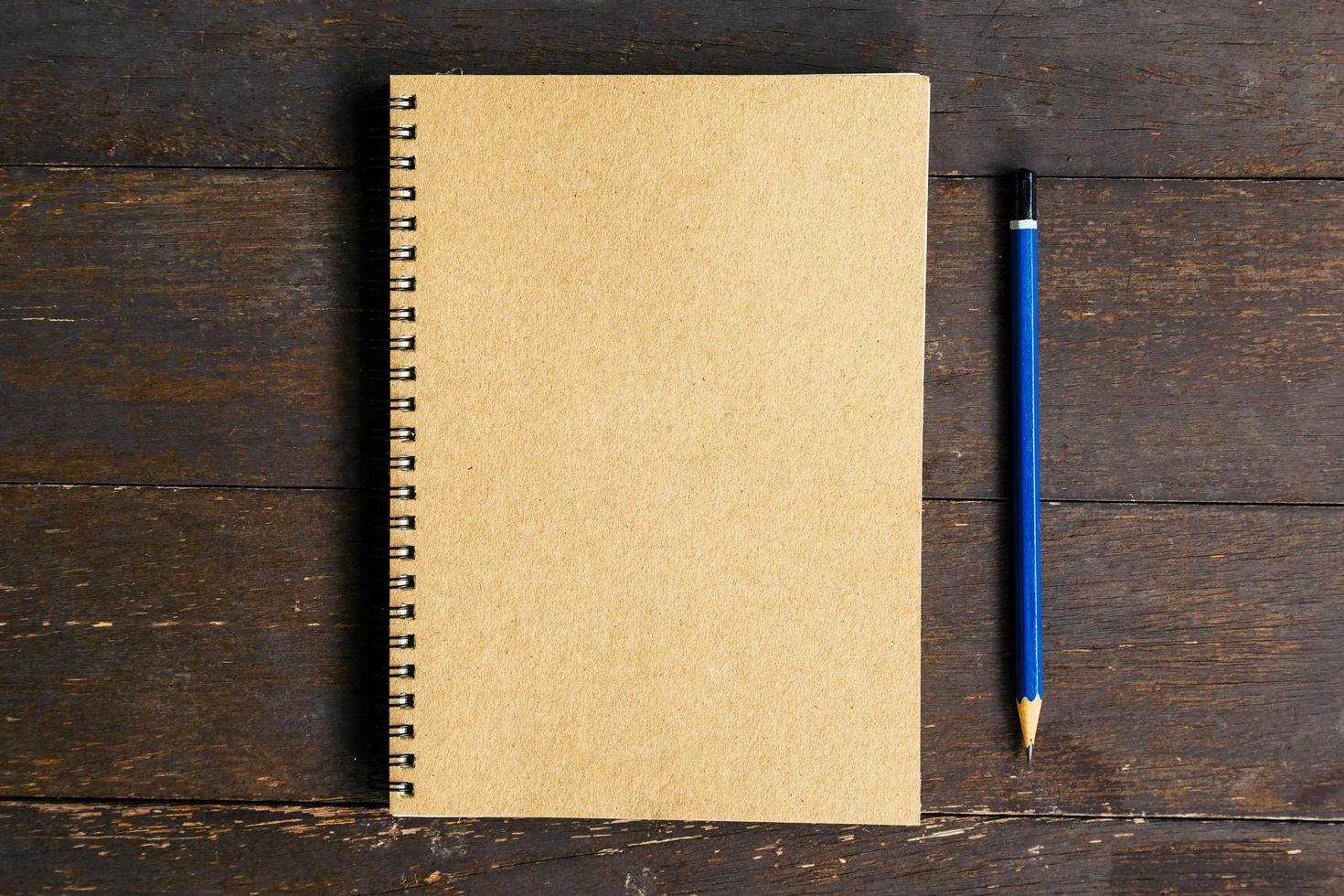 brown book and pencil on wood table background with space photo