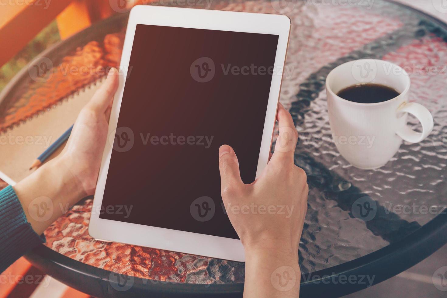 hand woman using tablet on table in coffee shop with vintage toned. photo