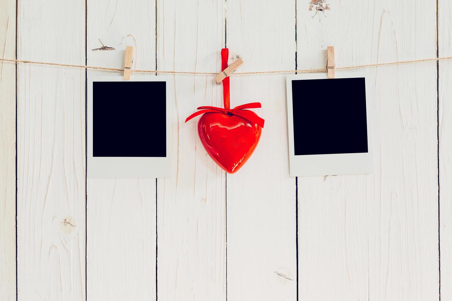 Two photo frame blank and red heart hanging on white wood with space. Valentine background.