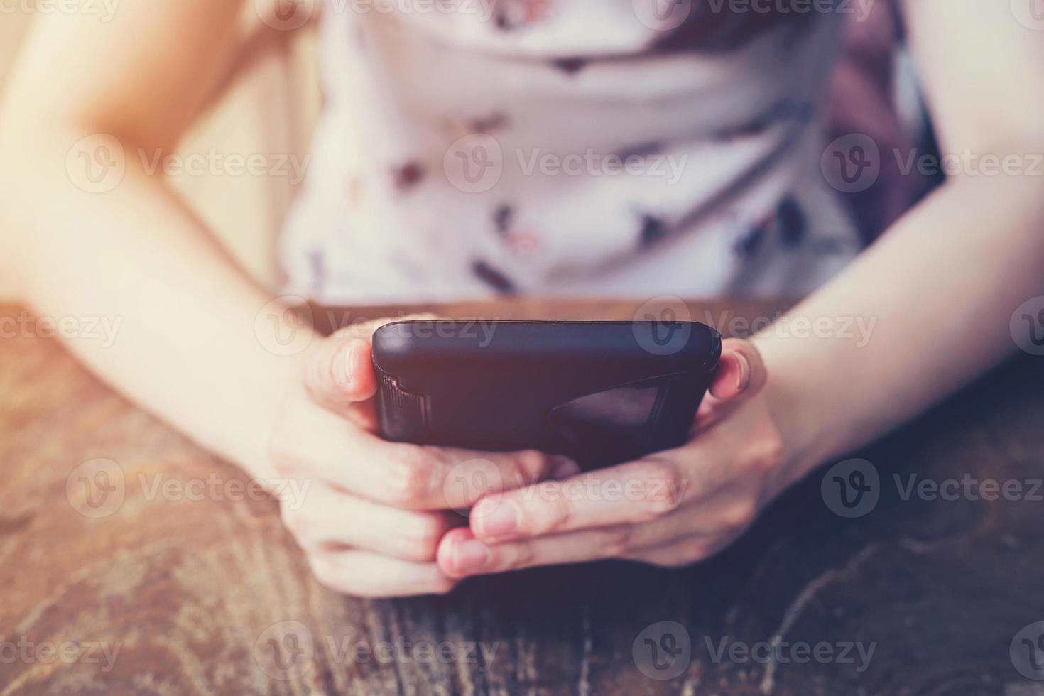 Close up of hand woman using phone in coffee shop with depth of field, Vintage toned. photo