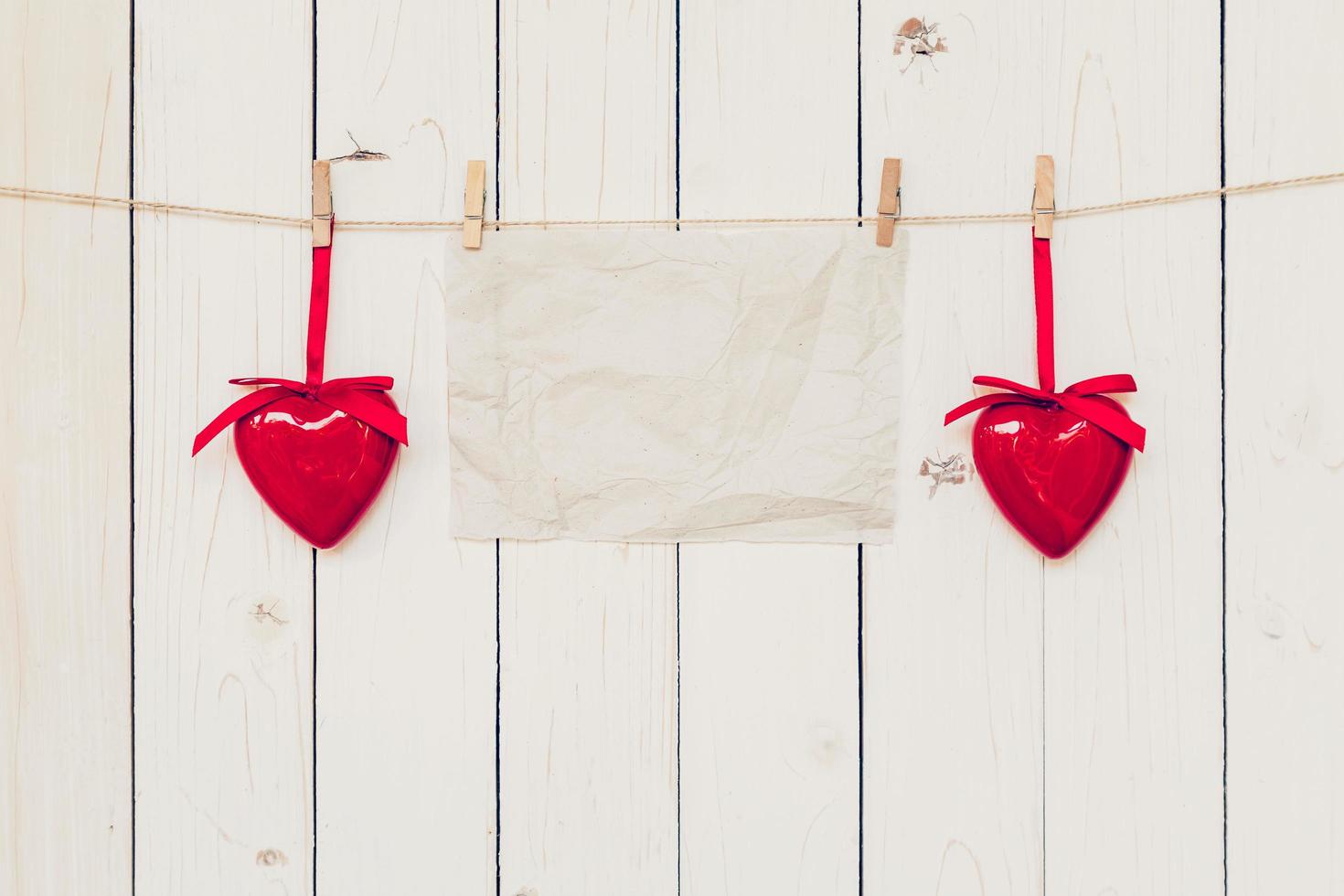 Blank old paper and red heart hanging on wood board background with space. photo