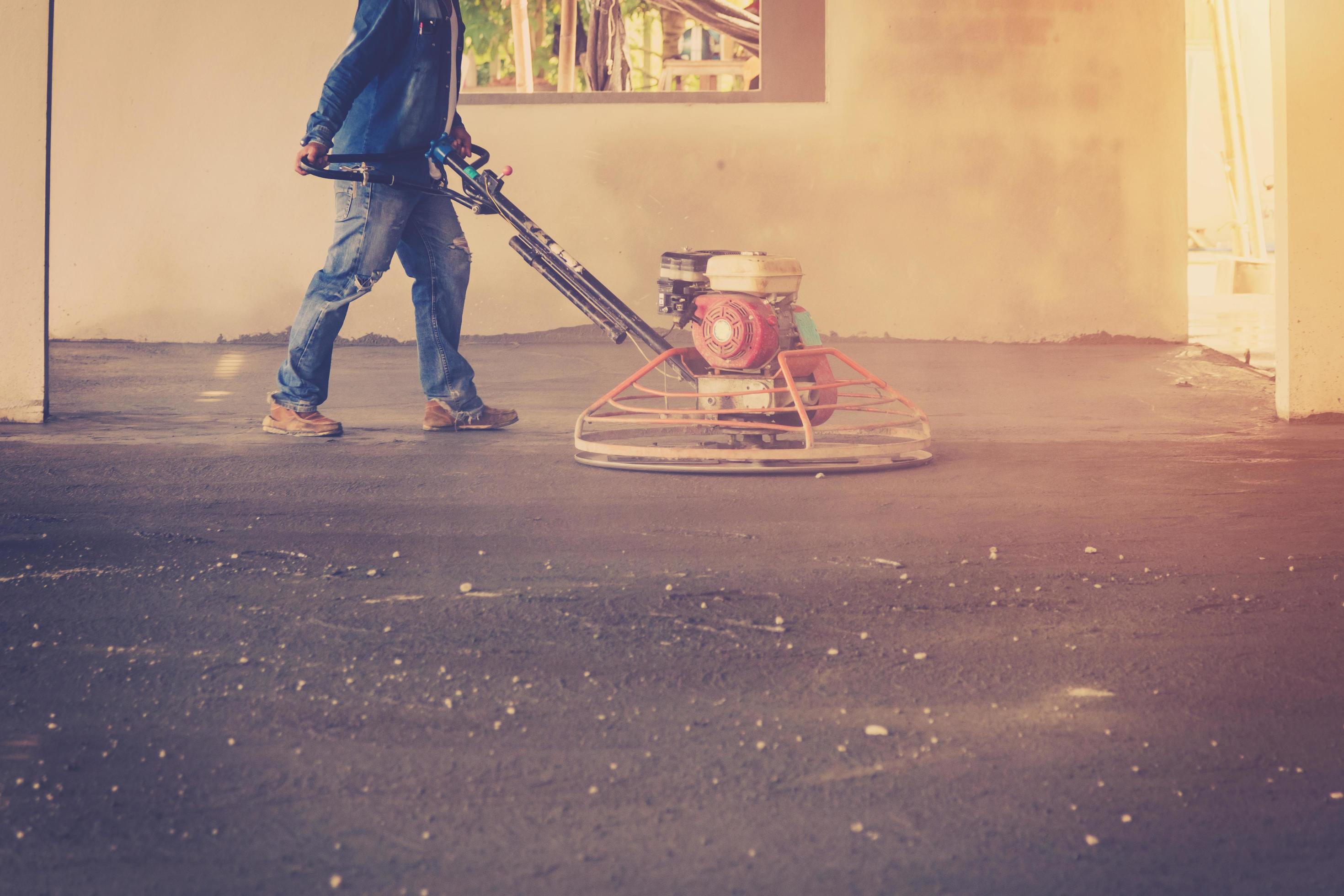 Plasterer working using scrubber machine for cement floor with vintage