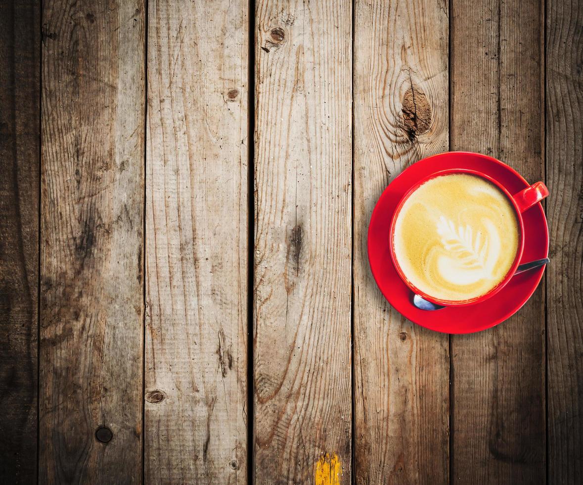 red cup and latte coffee on wood table with space photo